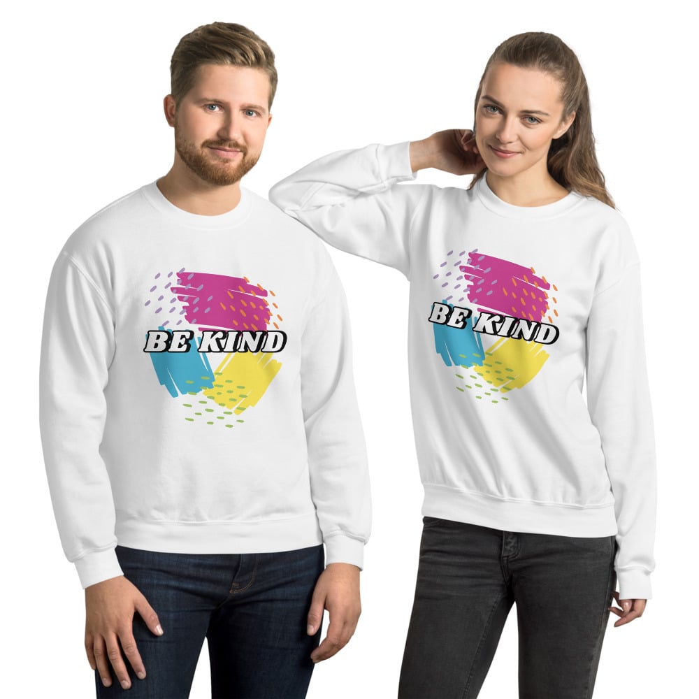 two people wearing white sweatshirts with pink, yellow, and blue scribbles that says be kind